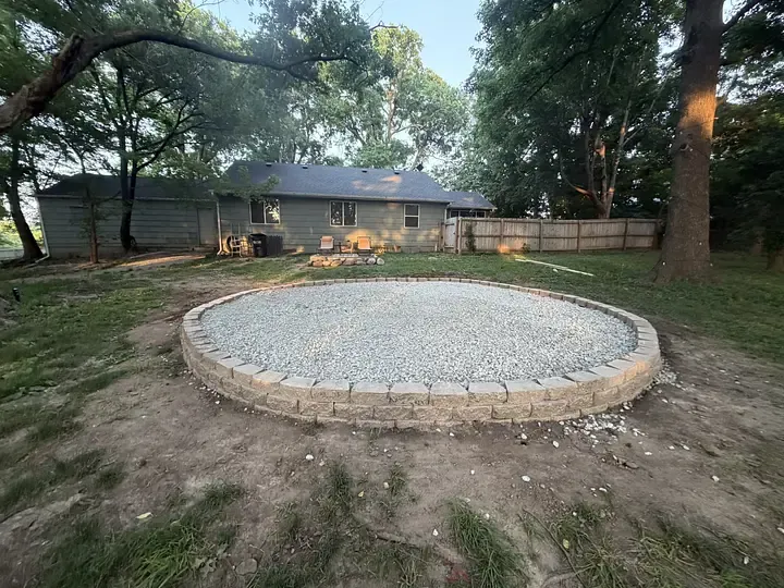 A circular patio excavated and its aggregate base graded and compacted — the part of a hardscape nobody sees and everything depends on.