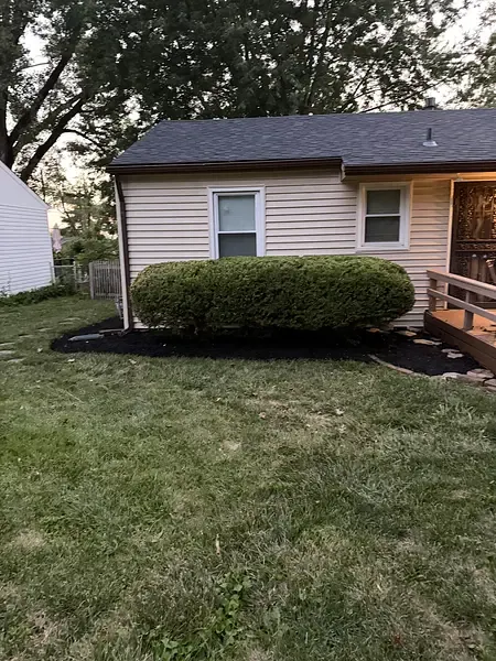 A ranch-house foundation bed cleaned out and re-mulched, with the shrubs cut back off the siding.
