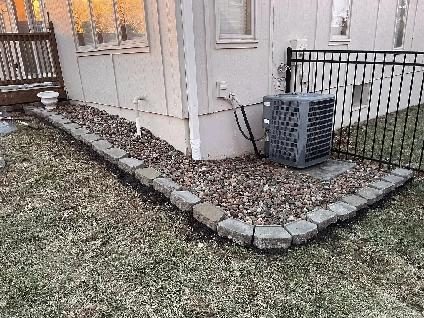 A river rock foundation strip edged in block, running out to an iron fence