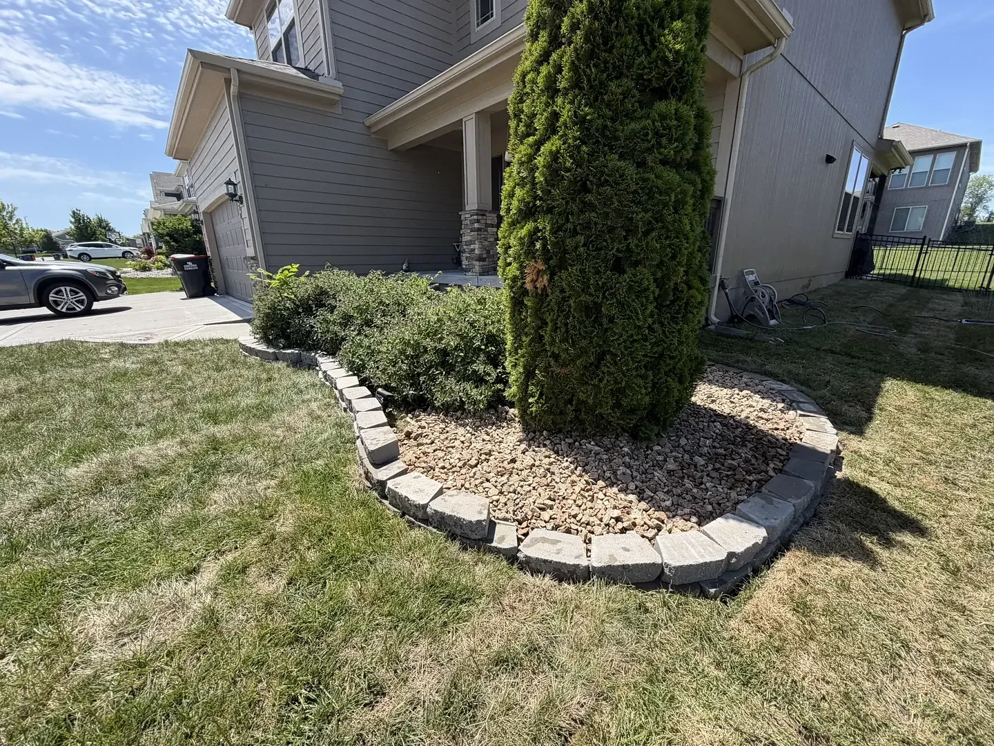 A new foundation planting with ornamental grasses, shrubs and a rock feature at a brick home
